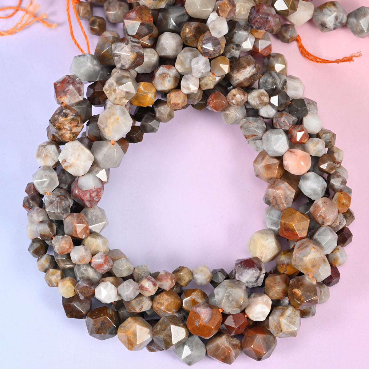 Gobi desert agate faceted diamond star cut beads, strands coiled into a ring showing the grey, cream and rust-brown mix
