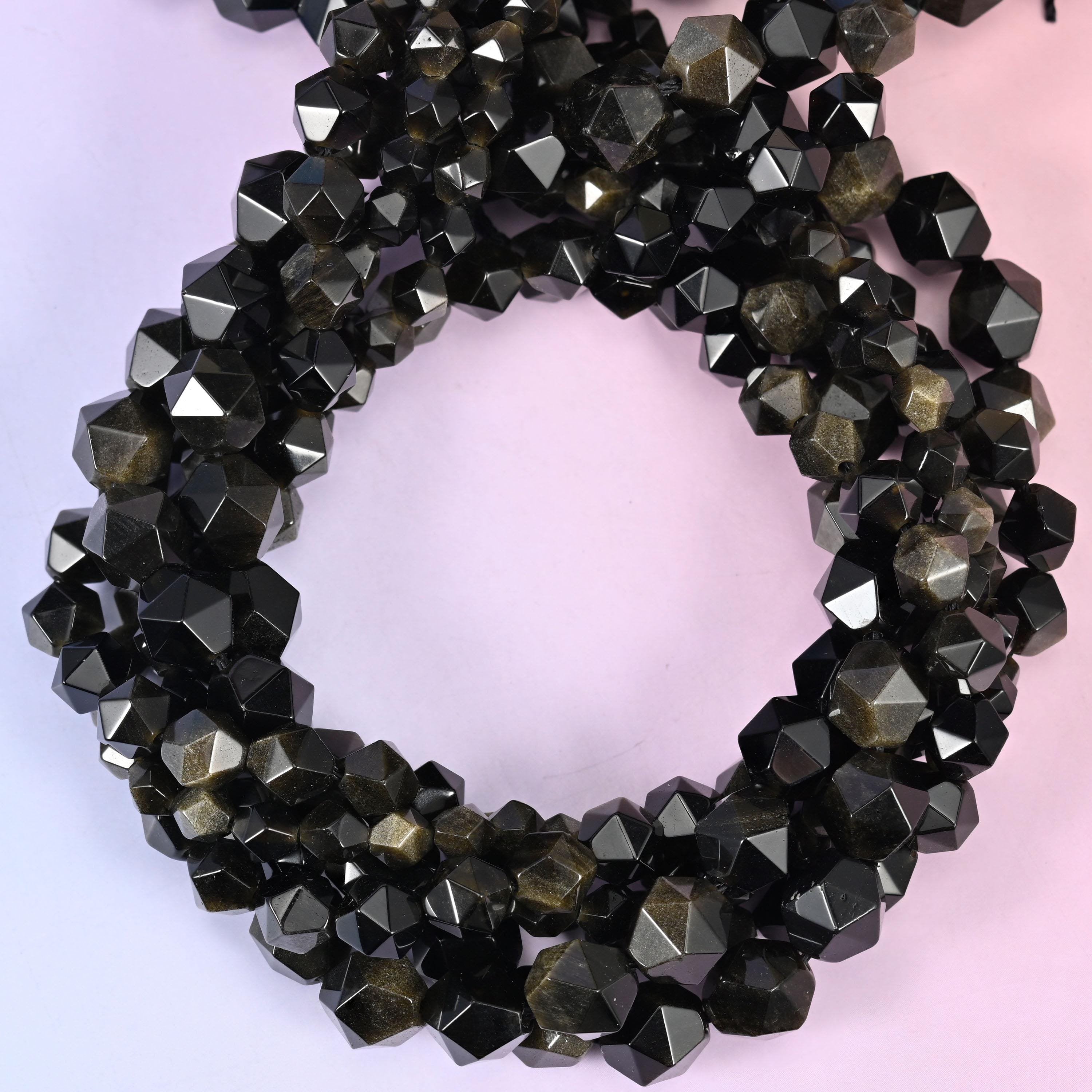 Gold obsidian faceted diamond star cut beads, strands coiled into a ring showing the black stone and its golden sheen