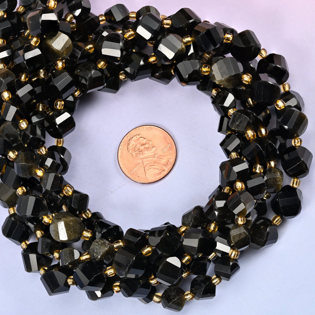 Gold Obsidian faceted spiral twist bead strands coiled around a US penny for size reference