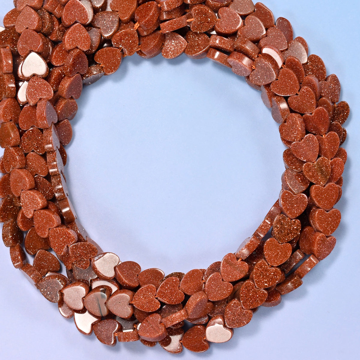 Gold Sandstone flat heart beads, close view of the coiled strands in coppery brown flecked with glitter