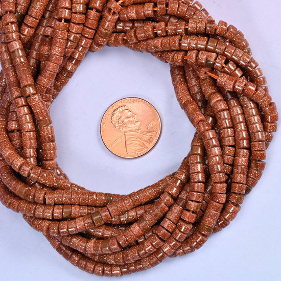 Gold Sandstone smooth heishi disc bead strands coiled around a US penny for size reference