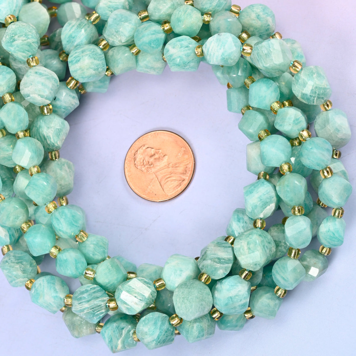 Green Amazonite faceted spiral twist bead strands coiled around a US penny for size reference