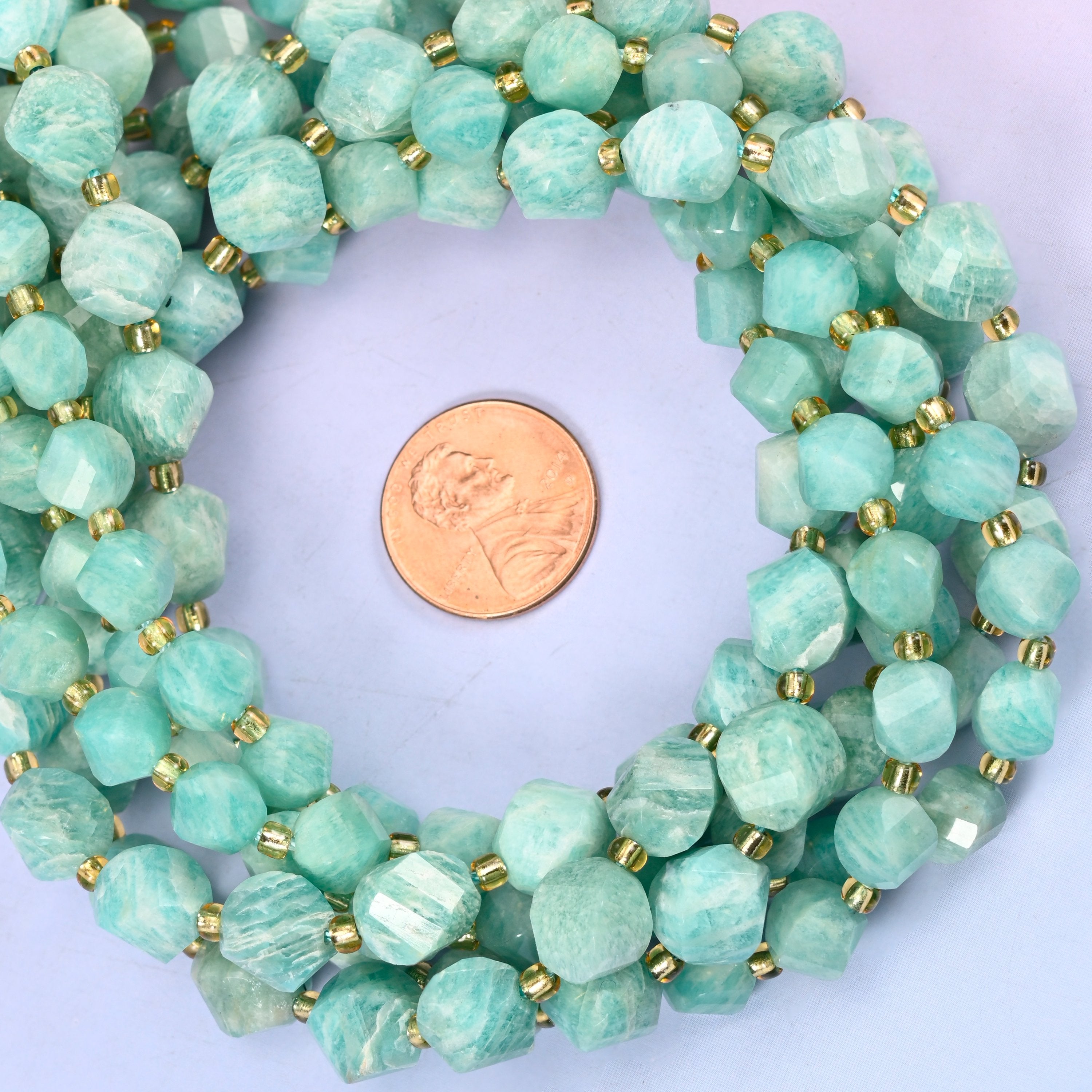 Green Amazonite faceted spiral twist bead strands coiled around a US penny for size reference