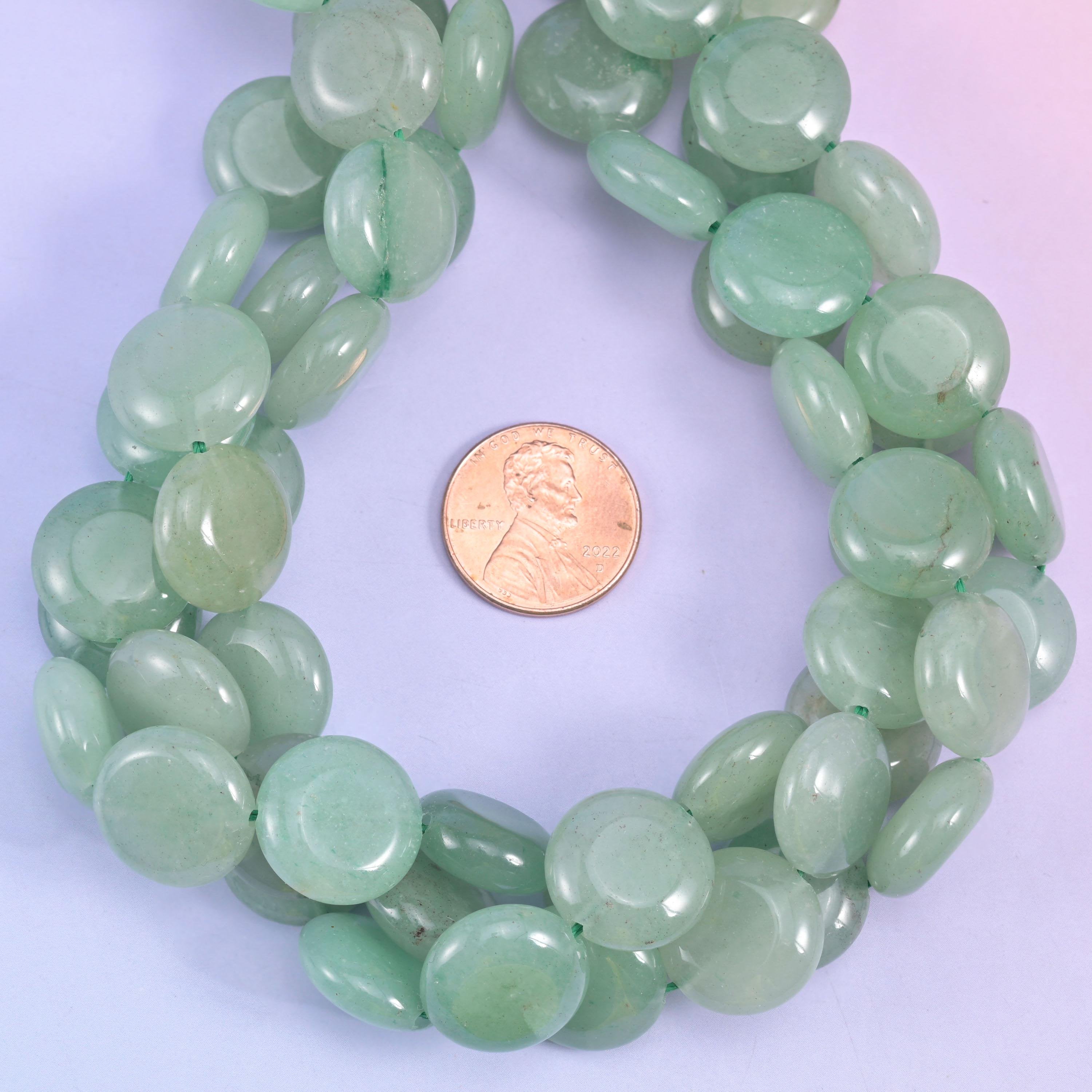 Green Aventurine smooth coin bead strands coiled around a US penny for size reference