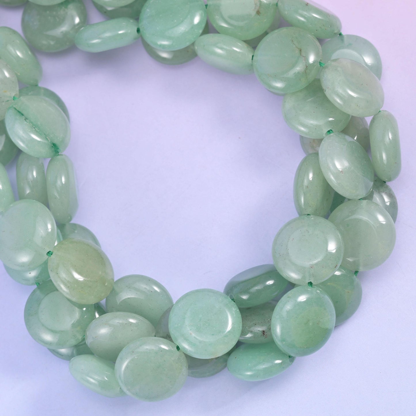 Green Aventurine smooth coin beads, close view of the coiled strands showing soft translucent green
