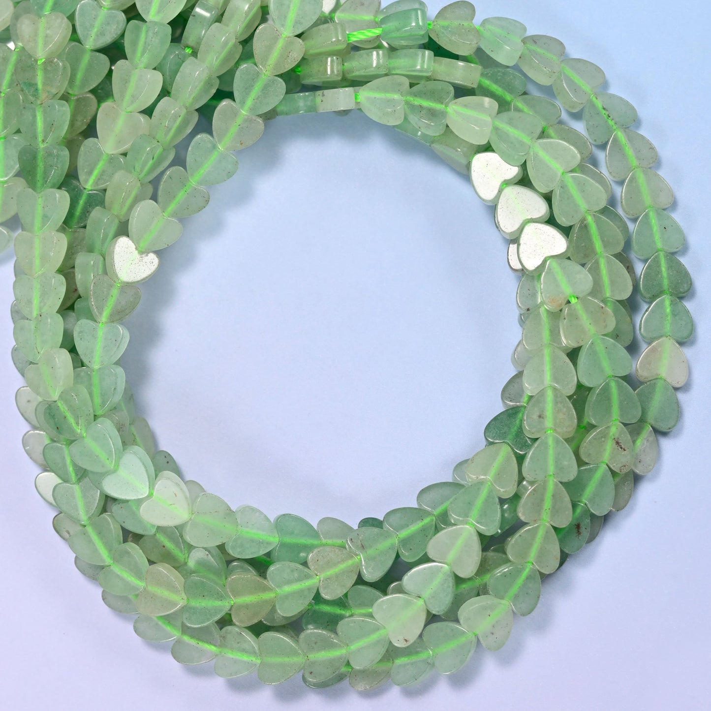 Green Aventurine flat heart beads, close view of the coiled strands in soft green