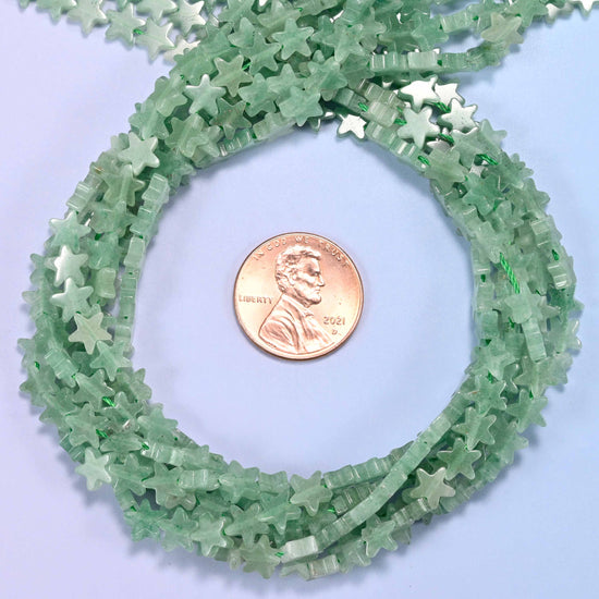 Green Aventurine flat star bead strands coiled around a US penny for size reference
