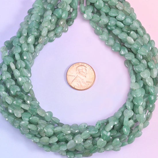 Green aventurine heart beads coiled into a loop around a US penny for size reference.