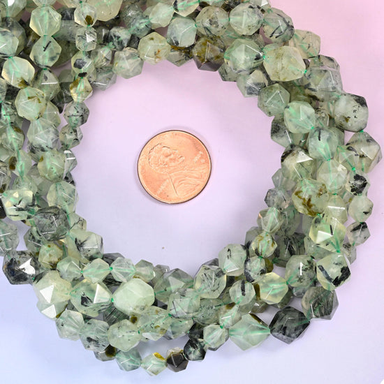 Green prehnite faceted diamond star cut bead strands coiled around a US penny for size reference