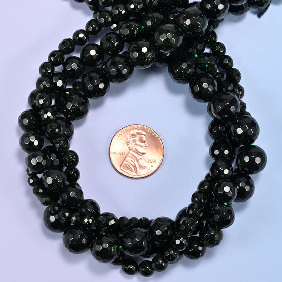 Green Sandstone faceted round bead strands coiled around a US penny for size reference