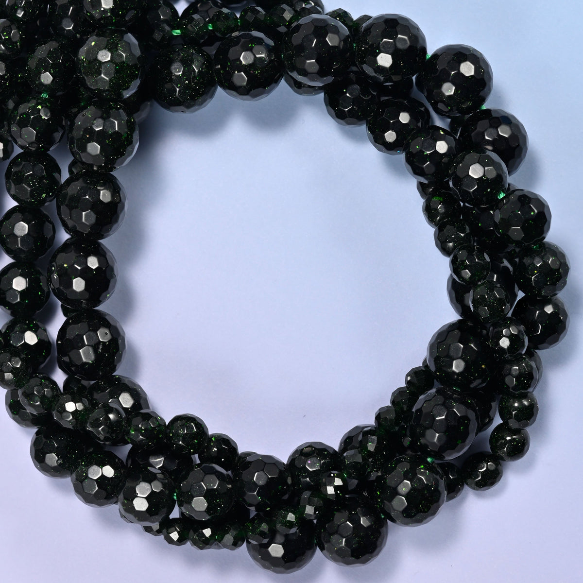 Green Sandstone faceted round beads, close view of the coiled strands showing near-black stone with fine green glitter