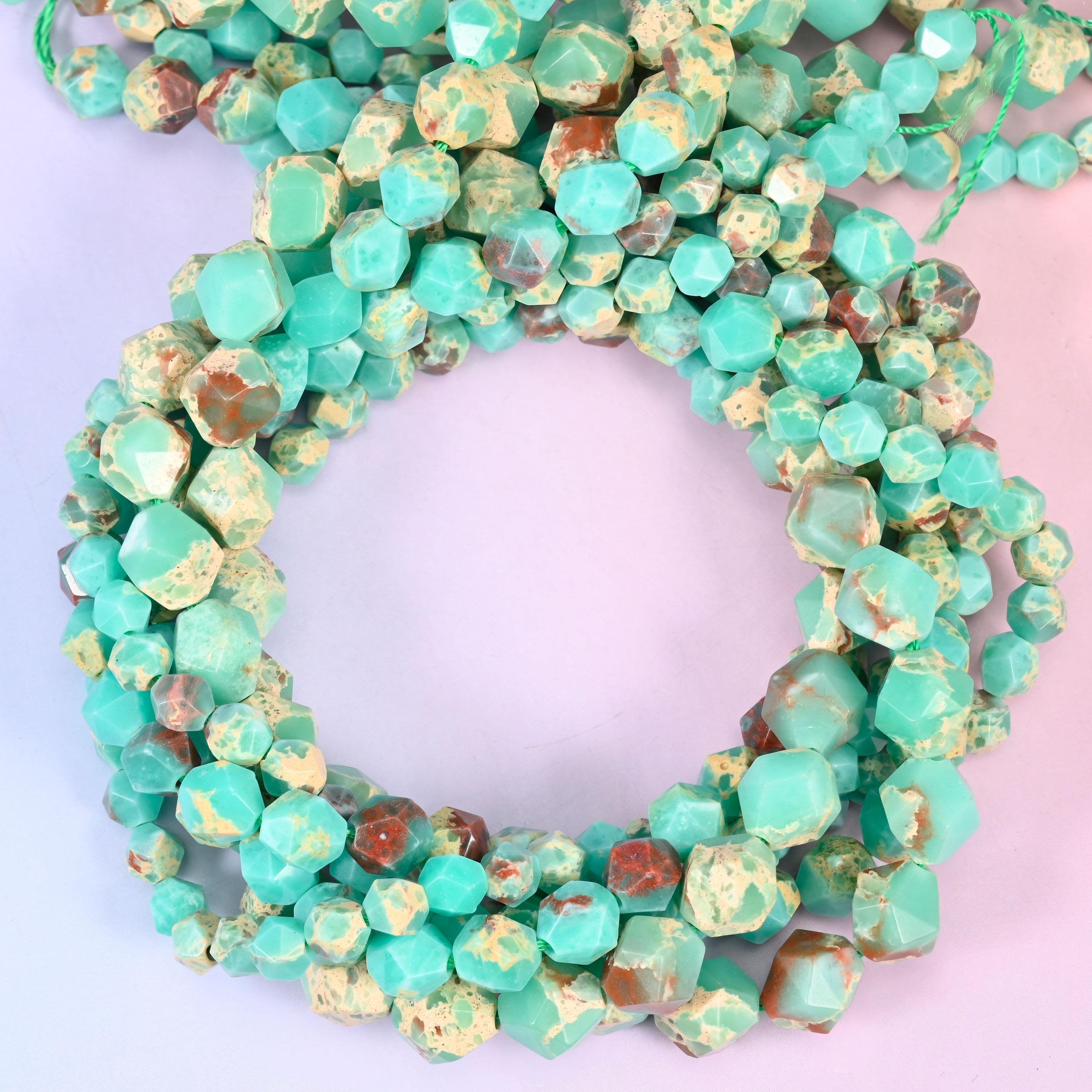Green Shoushan stone faceted diamond star cut beads, strands coiled into a ring showing the turquoise green stone with tan and rust markings
