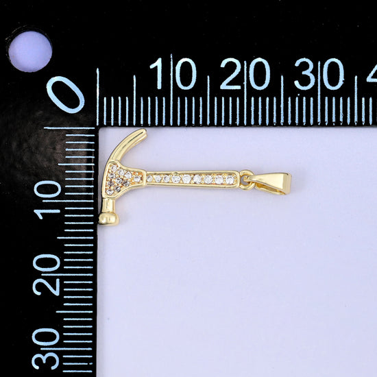 A hammer zircon charm shown lying sideways beside a millimetre ruler for scale