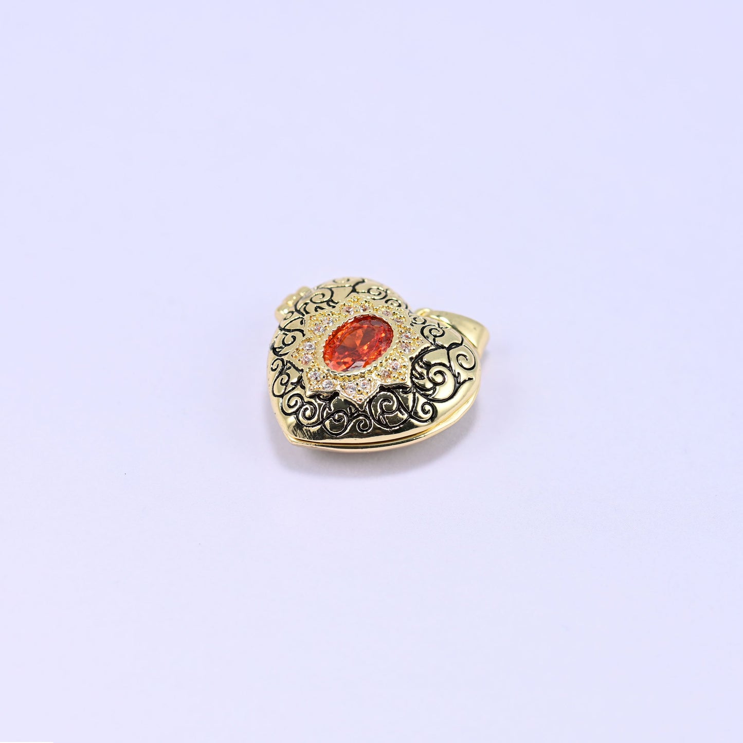 A heart locket charm with a filigree front and an orange oval stone, shown alone on a lilac background