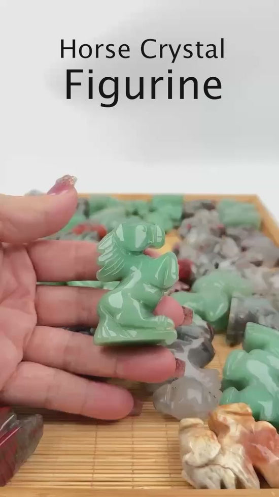 A hand lifting a green aventurine horse carving from a tray of the figurines