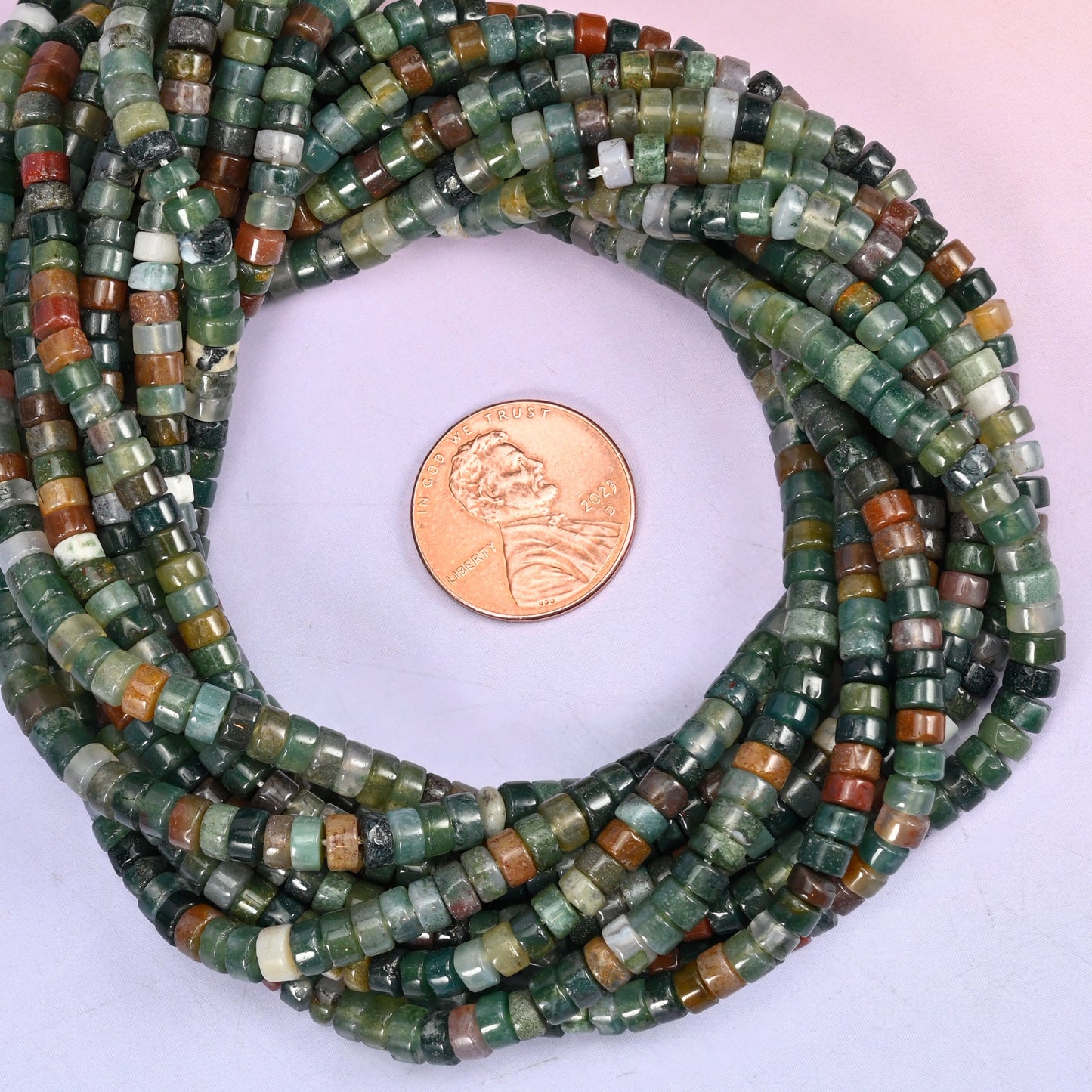 Indian Agate smooth heishi disc bead strands coiled around a US penny for size reference