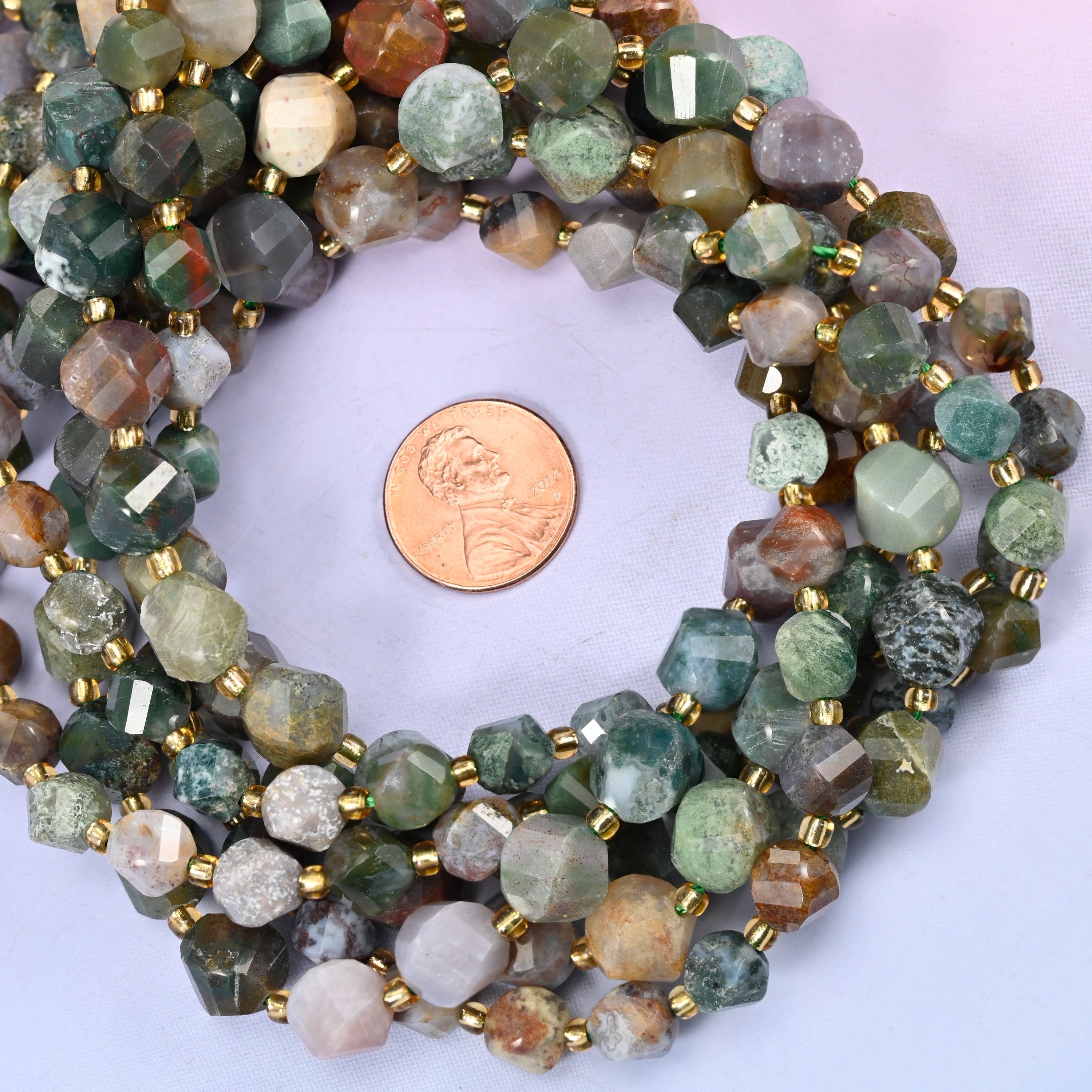 Indian Agate faceted spiral twist bead strands coiled around a US penny for size reference