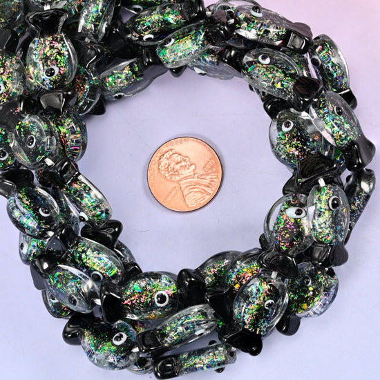 Iridescent Black Green Fish glass bead strands coiled around a US penny for size reference