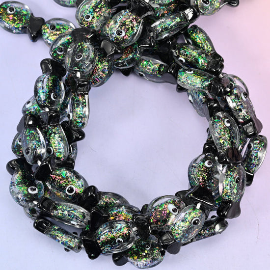 Iridescent Black Green Fish glass beads, close view of the coiled strands in smoky black with green and gold glitter inclusions