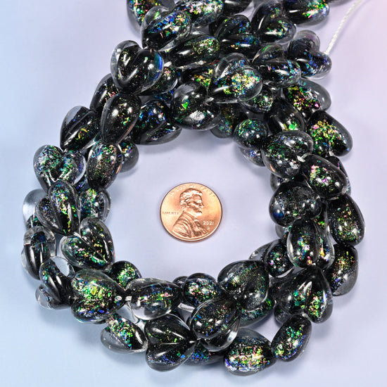 Iridescent Black Green Heart glass bead strands coiled around a US penny for size reference