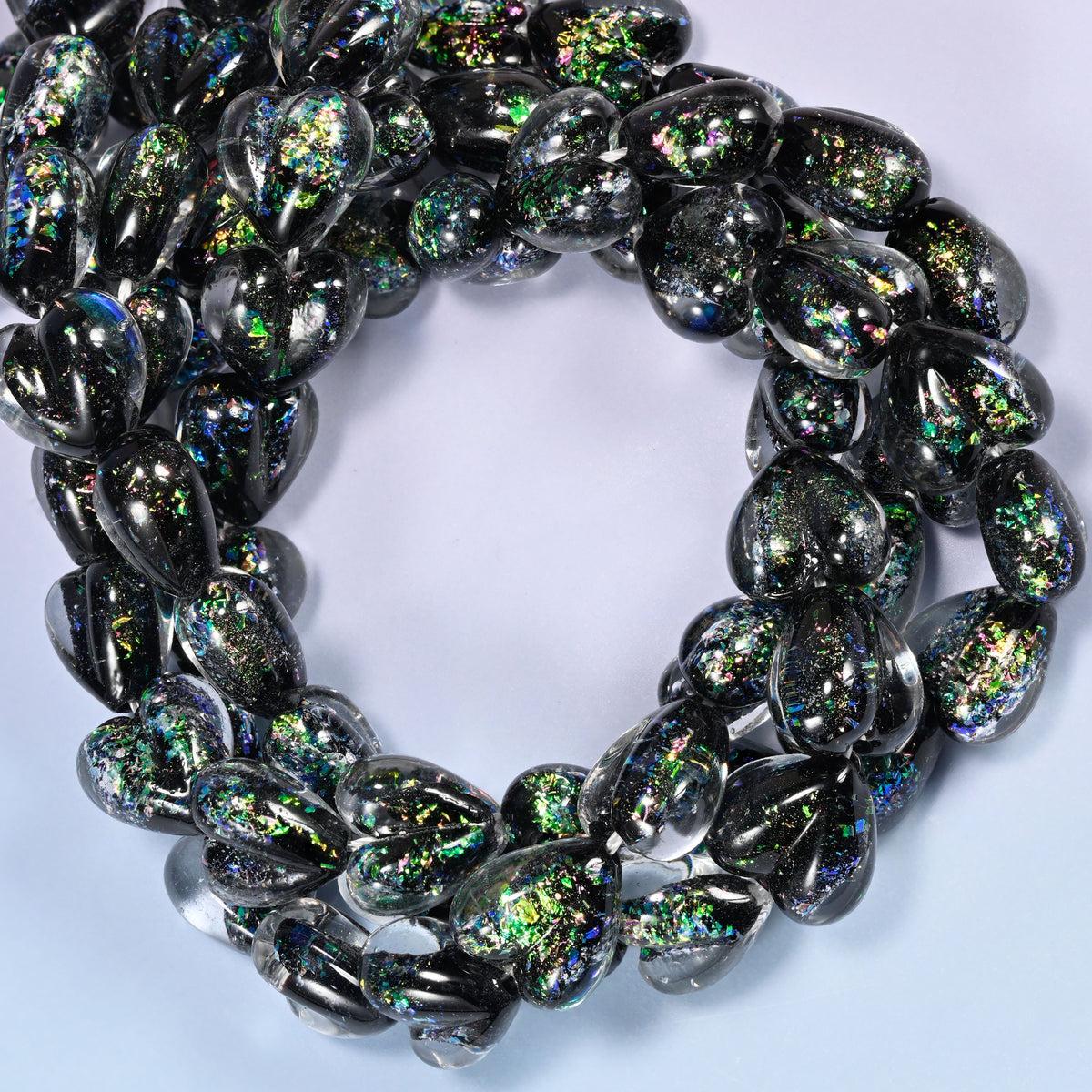 Iridescent Black Green Heart glass beads, close view of the coiled strands in black with green and gold glitter inclusions