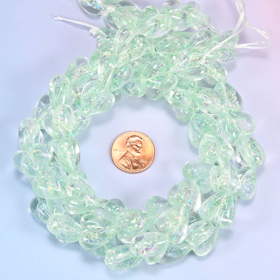 Iridescent Light Green Heart glass bead strands coiled around a US penny for size reference