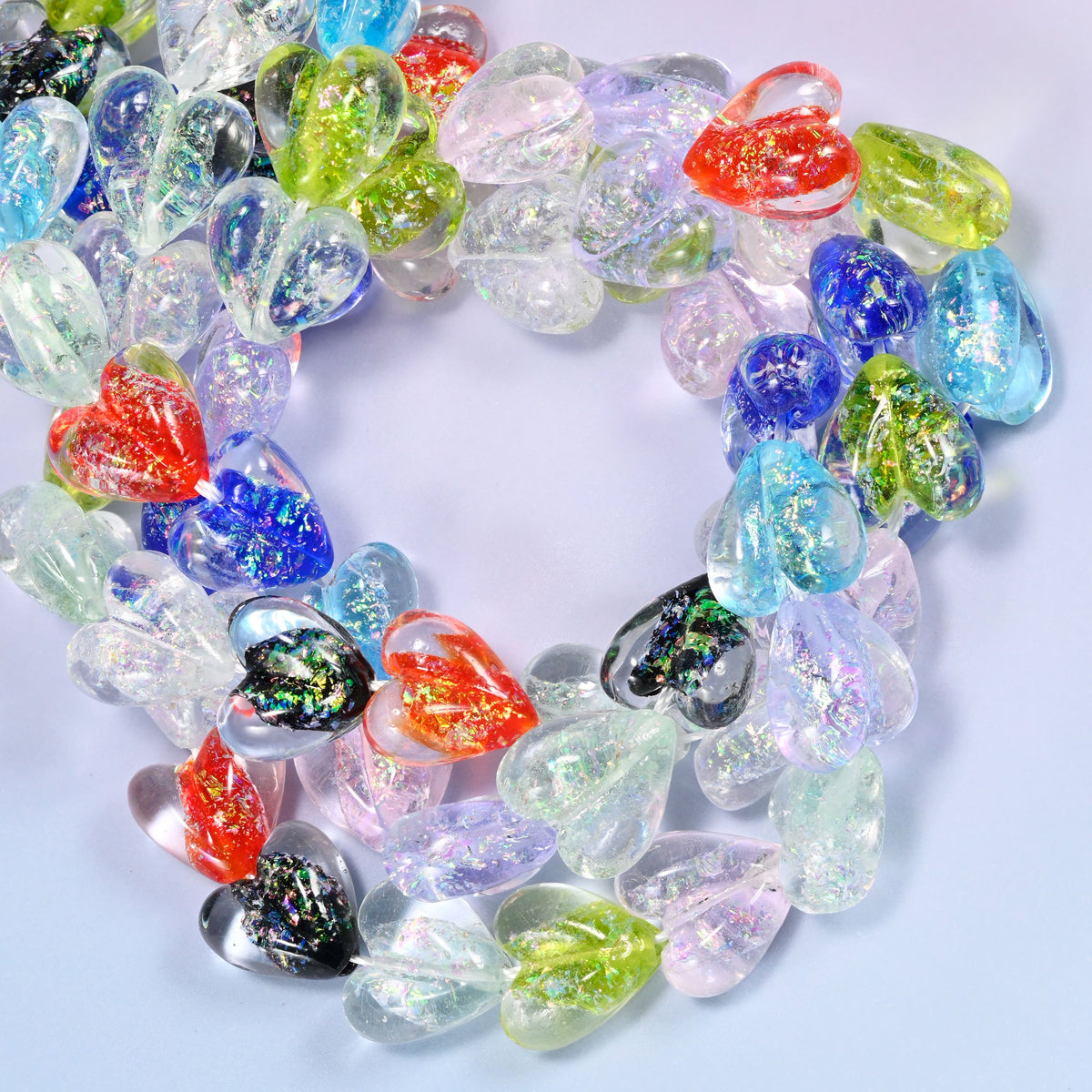 Iridescent Multicolor Heart glass beads, close view of the coiled strands mixing clear, blue, red, green and black hearts