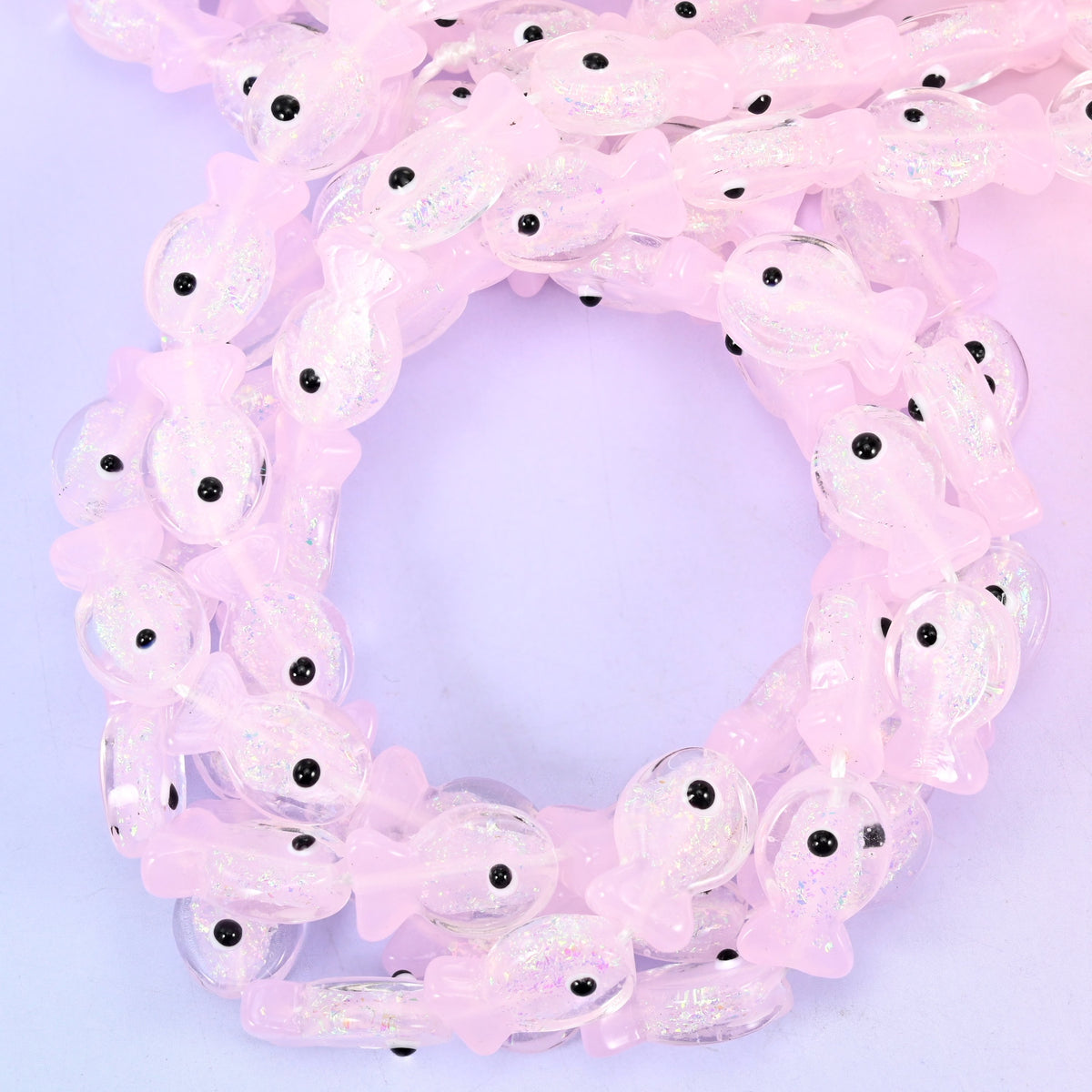 Iridescent Pink Fish glass beads, close view of the coiled strands in soft pink with a pearly sheen