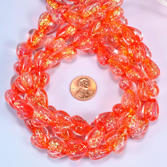 Iridescent Red Heart glass bead strands coiled around a US penny for size reference