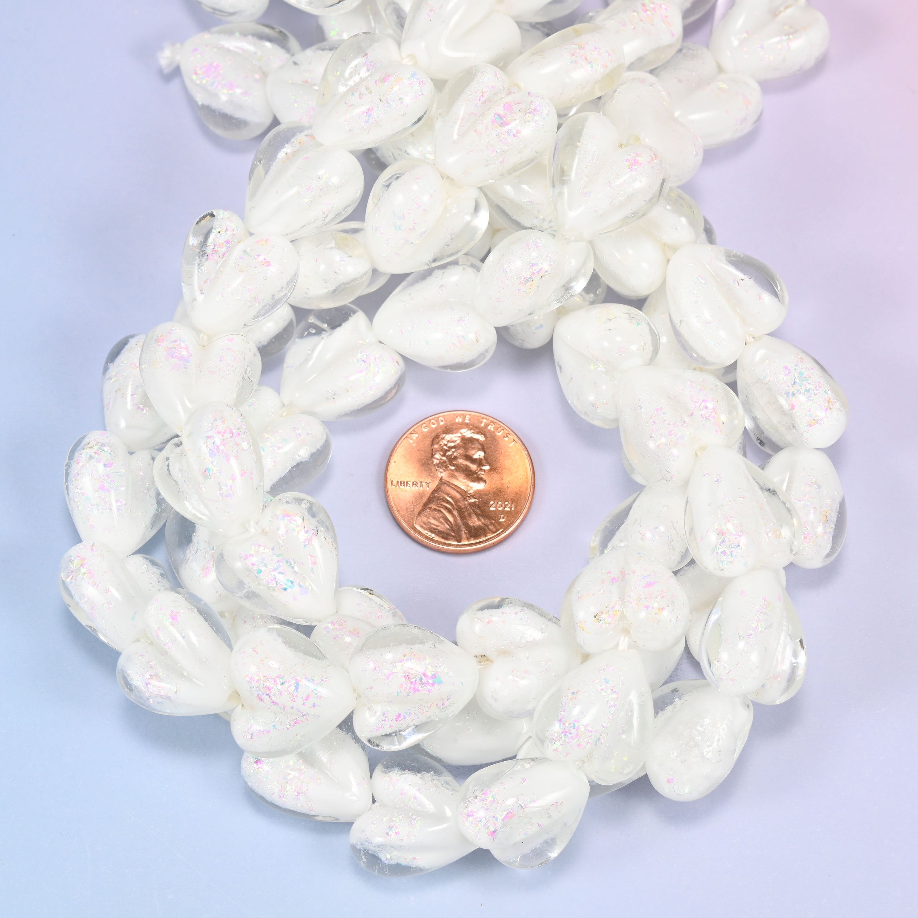 Iridescent White Heart glass bead strands coiled around a US penny for size reference