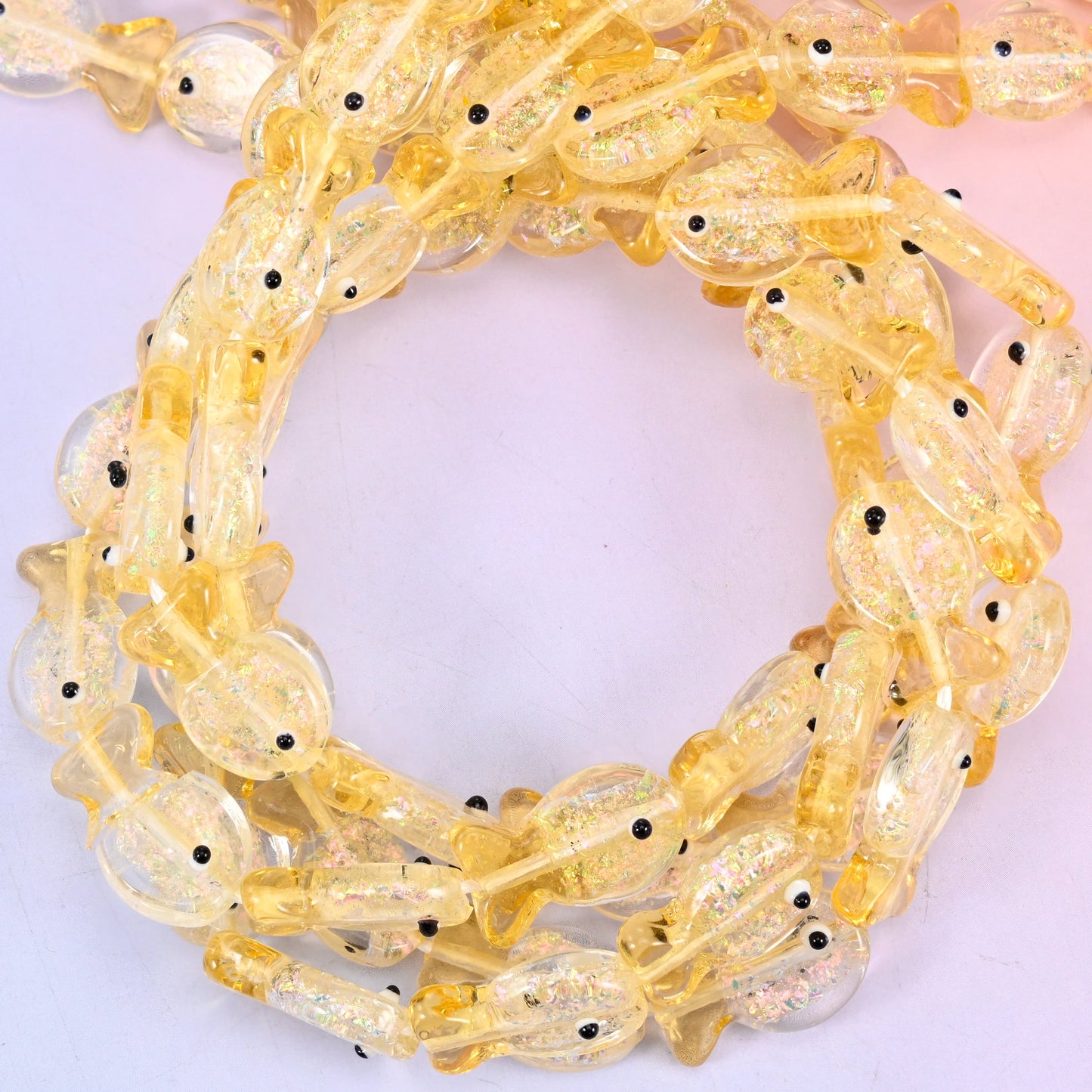 Iridescent Yellow Fish glass beads, close view of the coiled strands in soft golden yellow with glitter inclusions