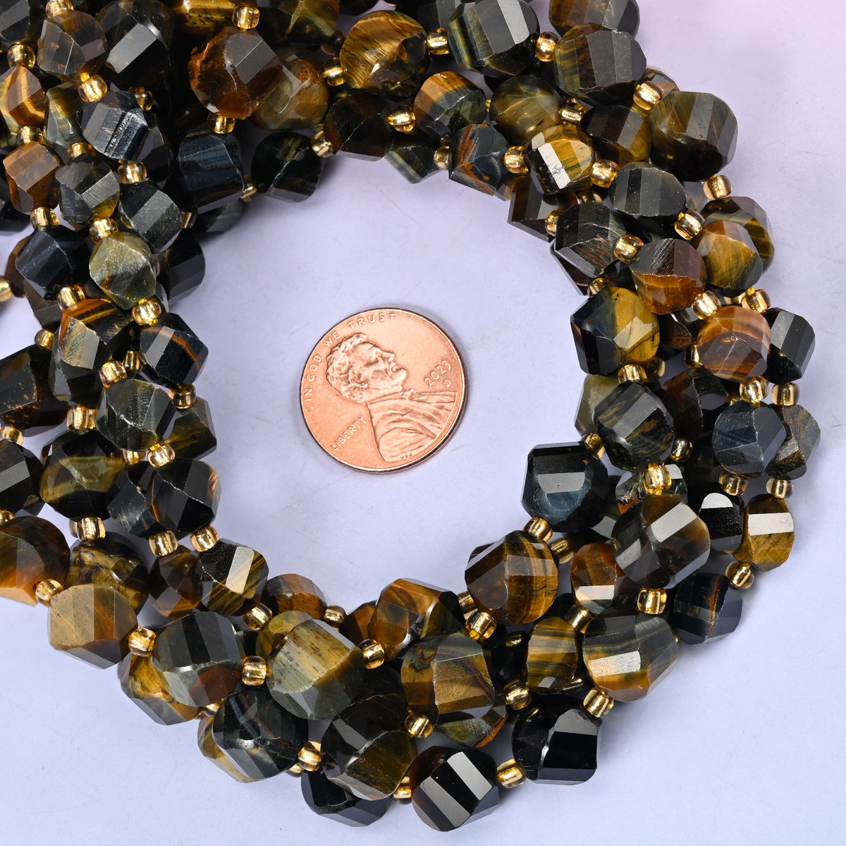 Iron Tiger Eye faceted spiral twist bead strands coiled around a US penny for size reference