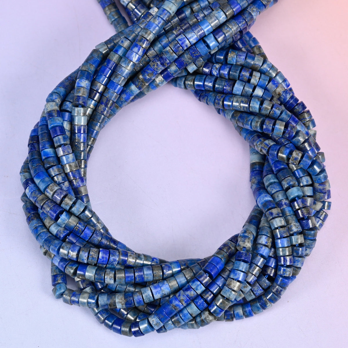 Lapis smooth heishi disc beads, close view of the coiled strands showing deep blue with grey and white veining