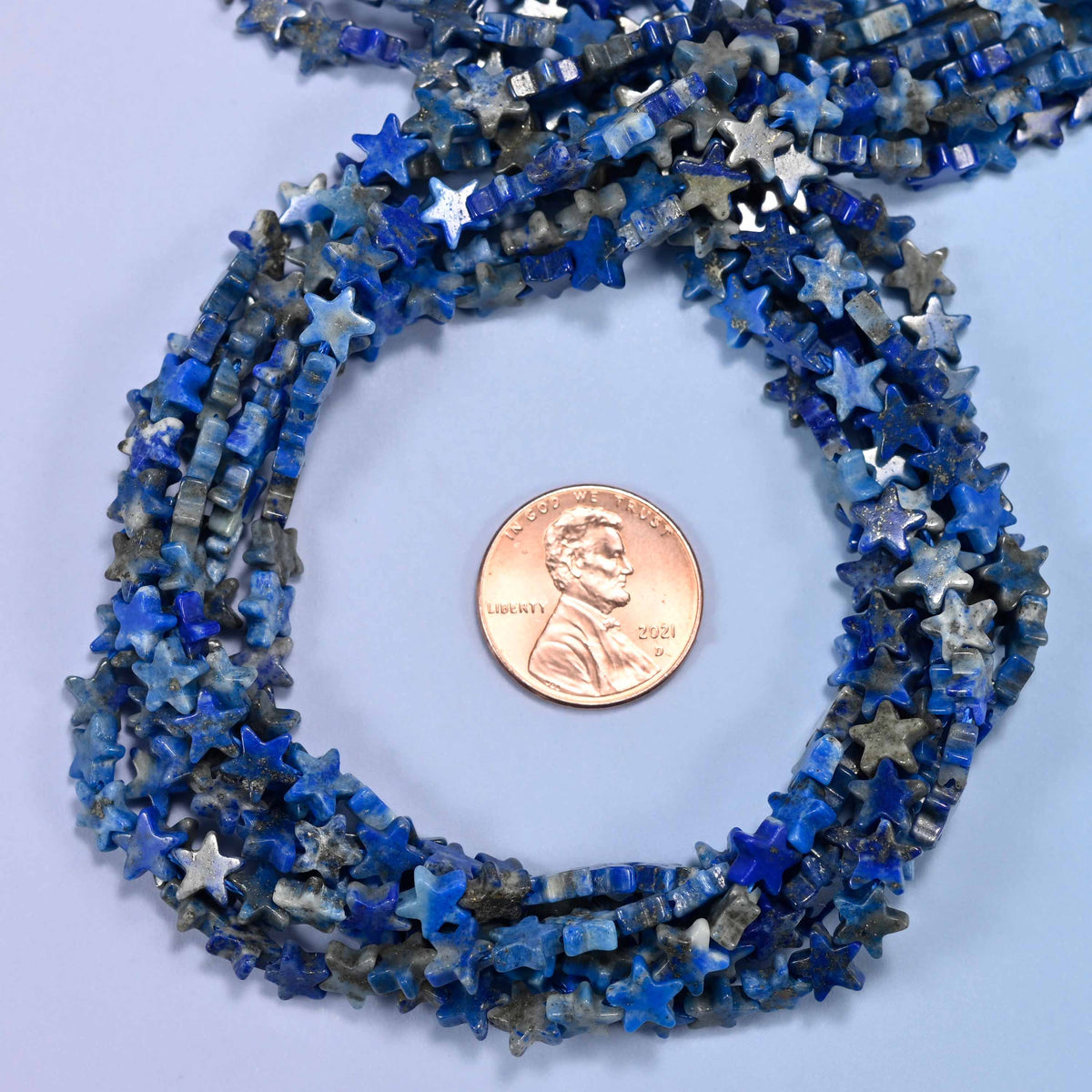 Lapis Lazuli flat star bead strands coiled around a US penny for size reference