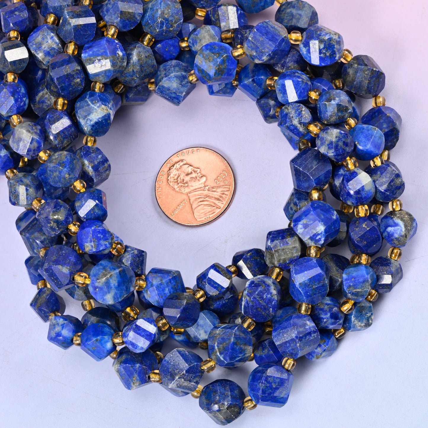 Lapis Lazuli faceted spiral twist bead strands coiled around a US penny for size reference