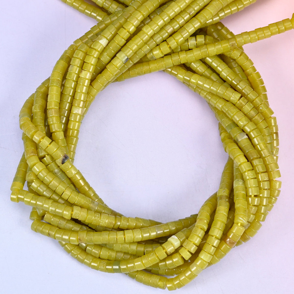Lemon Jade smooth heishi disc beads, close view of the coiled strands showing the even olive-yellow colour