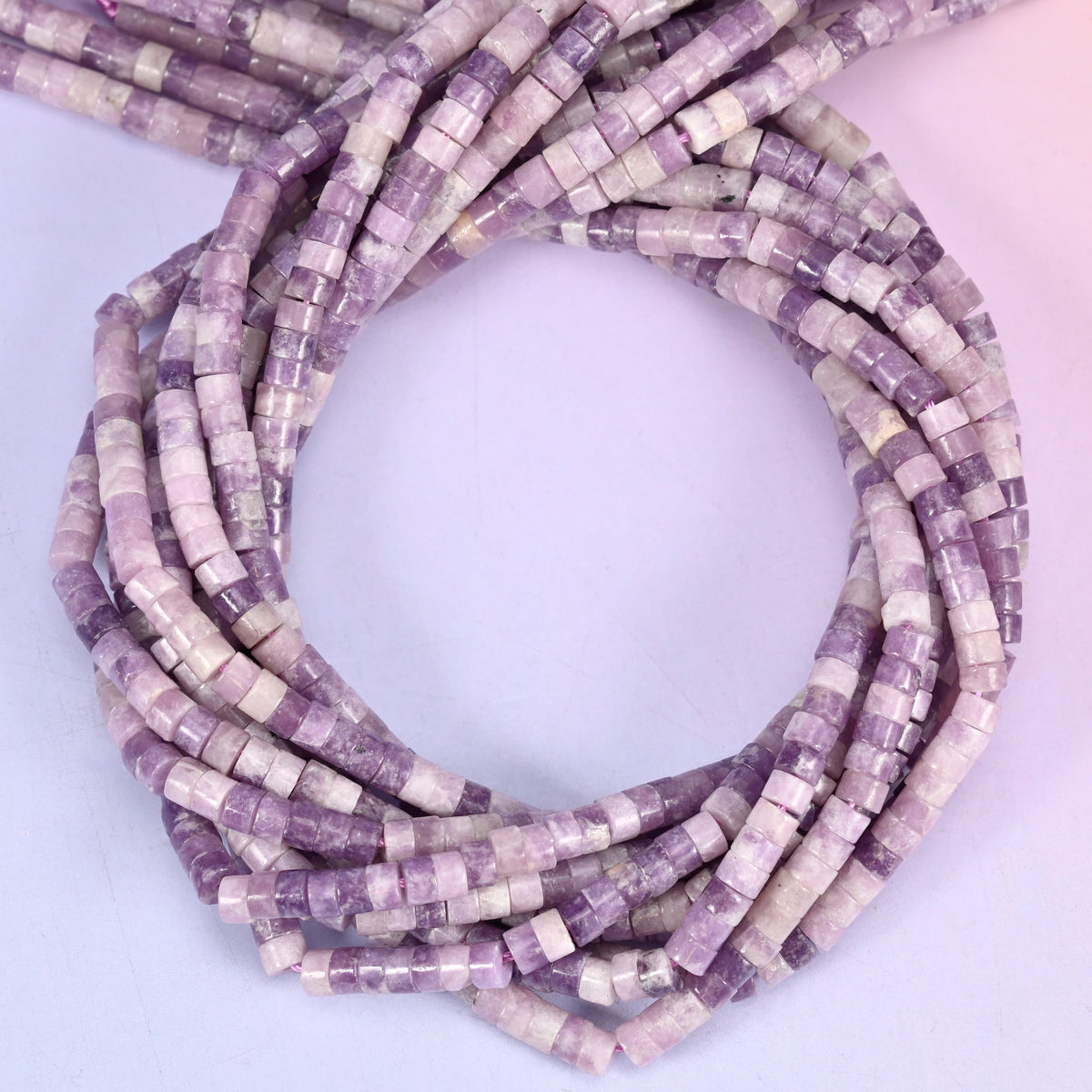 Lepidolite smooth heishi disc beads, close view of the coiled strands showing lilac purple with cream and grey banding