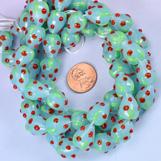 Light Blue Red Dots Strawberry glass bead strands coiled around a US penny for size reference
