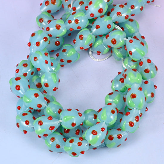 Light Blue Red Dots Strawberry glass beads, close view of the coiled strands in pale blue with green leaf panels and red seed dots