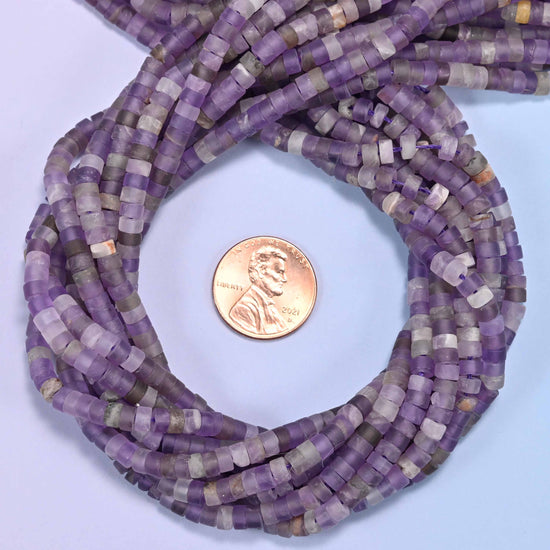 Matte Amethyst heishi disc bead strands coiled around a US penny for size reference