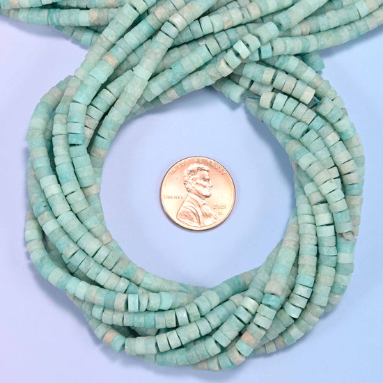 Matte Blue Amazonite heishi disc bead strands coiled around a US penny for size reference