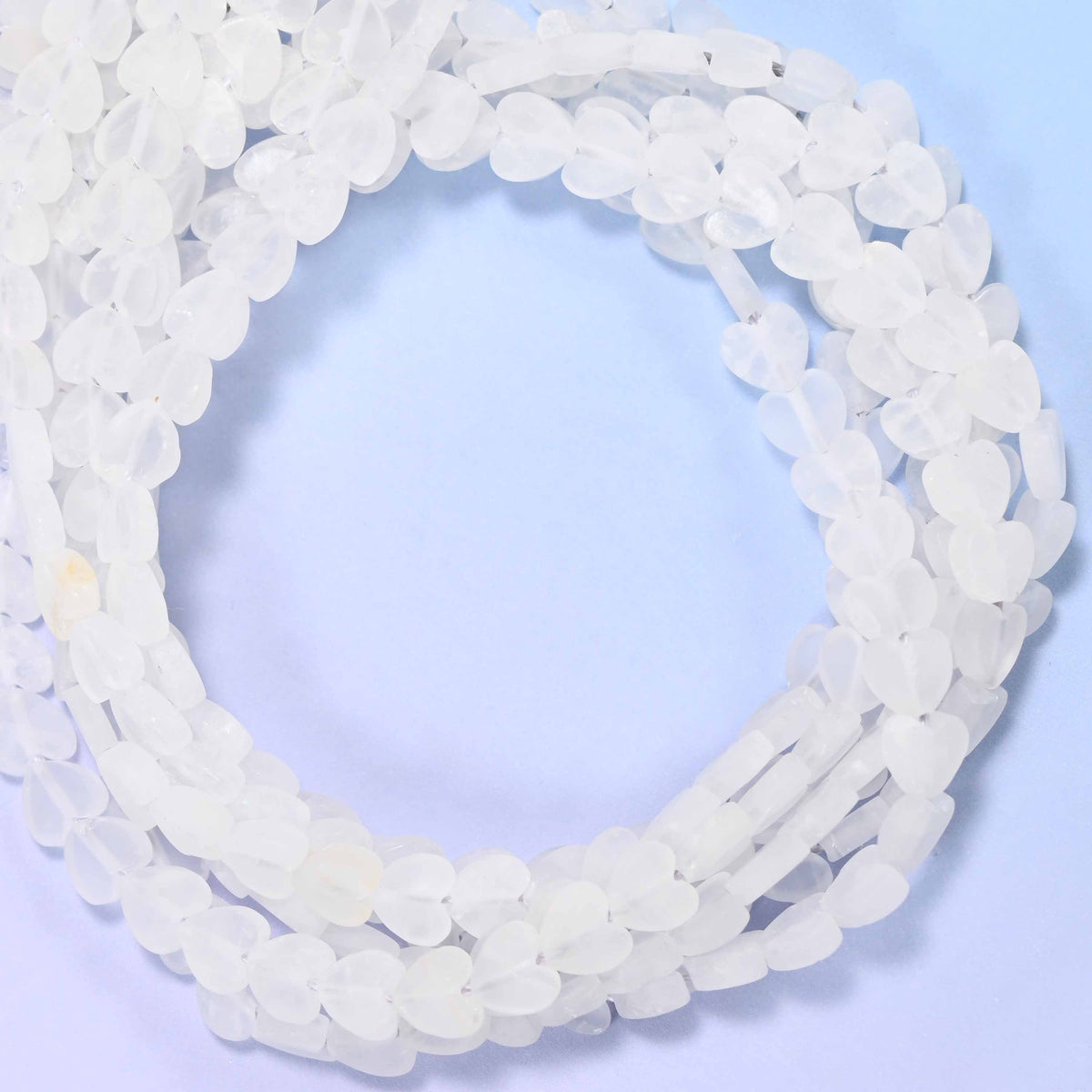 Matte Clear Quartz flat heart beads, close view of the coiled strands of frosted white hearts