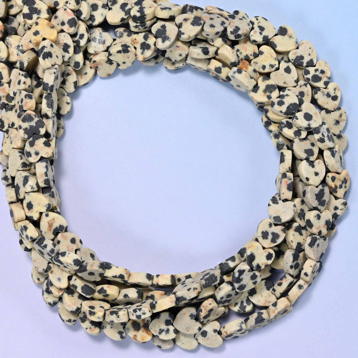 Matte Dalmatian Jasper flat heart beads, close view of the coiled strands in cream with black spotting and a matte finish