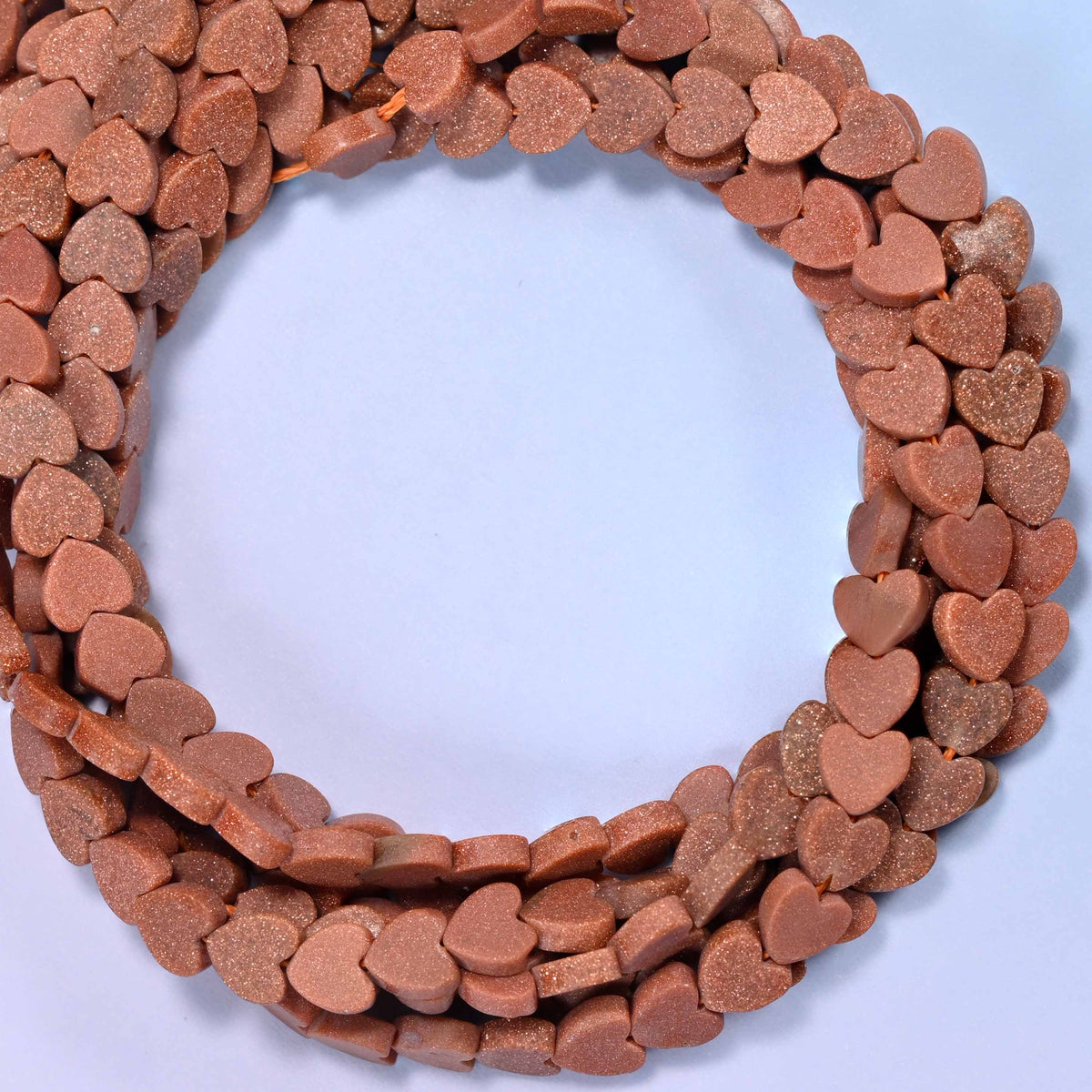 Matte Gold Sandstone flat heart beads, close view of the coiled strands in coppery brown with a matte finish