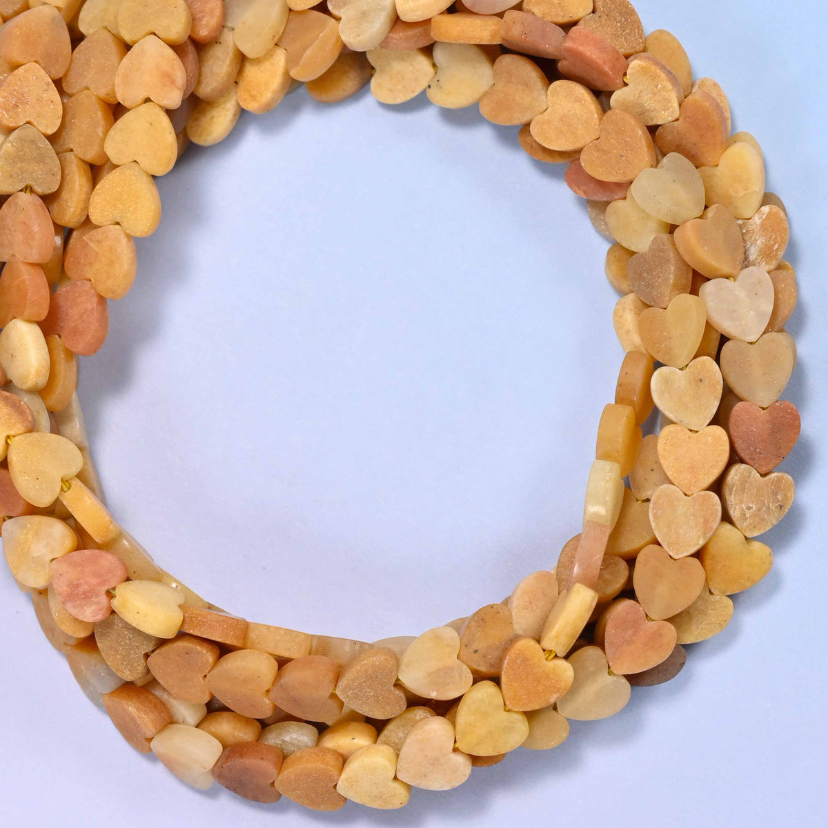 Matte Gold Silk Jade flat heart beads, close view of the coiled strands in honey gold and cream