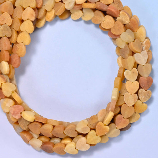 Matte Gold Silk Jade flat heart beads, close view of the coiled strands in honey gold and cream