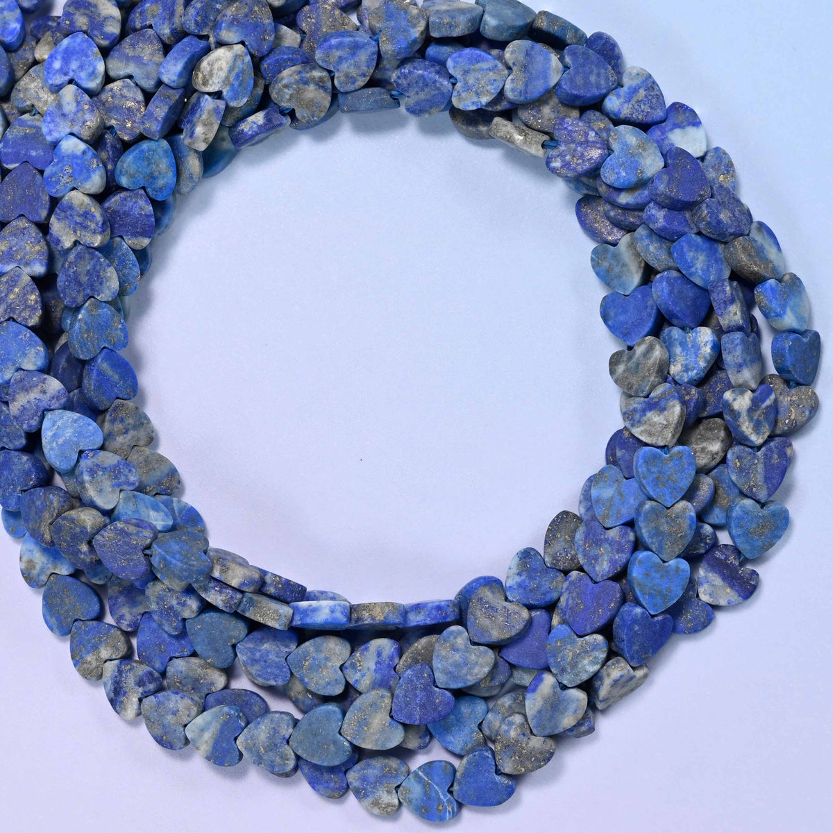 Matte Lapis Lazuli flat heart beads, close view of the coiled strands in deep blue with grey marbling