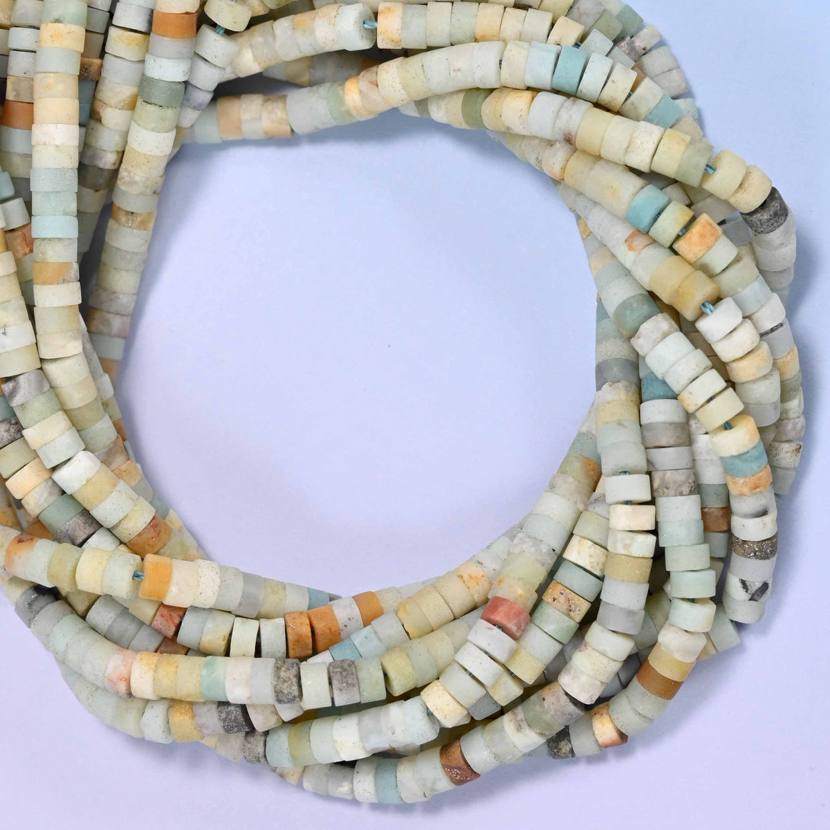 Matte Multicolor Amazonite heishi disc beads, close view of the coiled strands mixing sea green, cream, amber and grey