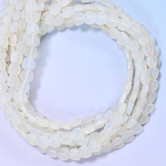 Matte Opalite flat heart beads, close view of the coiled strands of milky white hearts with a matte finish