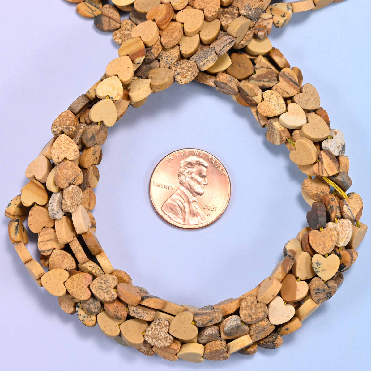 Matte Picture Jasper flat heart bead strands coiled around a US penny for size reference